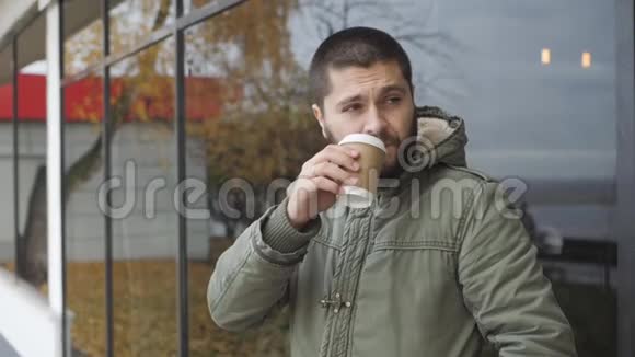英俊的小胡子拿着一个杯子在户外的秋天喝热饮咖啡或茶视频的预览图