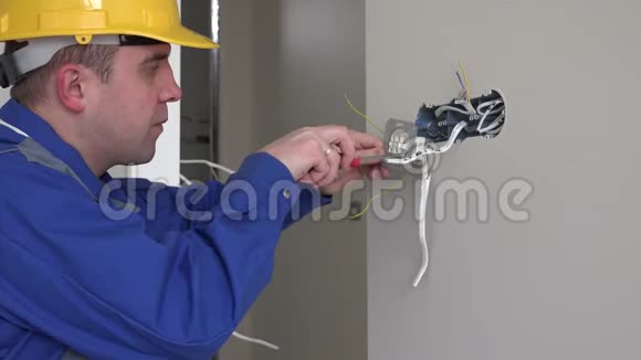 年轻电工与墙壁插座和螺丝刀安装插座视频的预览图