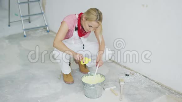 女人在桶里混合墙壁油漆视频的预览图