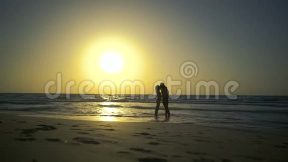 浪漫的夫妻正在水中的海滩上坠入爱河男人和女人牵着手走在金色的道路上视频的预览图