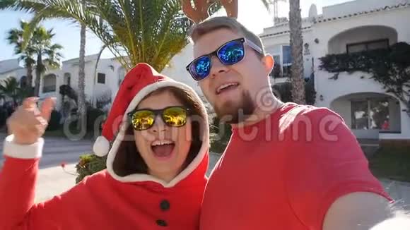 圣诞老人帽子上的快乐情侣在夏天的户外用手拍自拍照片视频的预览图