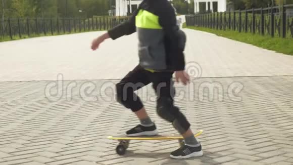 一个戴着保护头盔的学龄前男孩在公园里骑滑板夏季视频的预览图