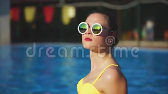 穿着泳衣和太阳镜的时髦女人微笑着夏天坐在外面视频的预览图