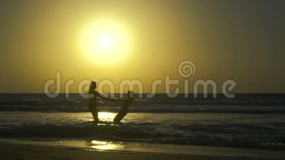 浪漫的年轻夫妇在日落时在海滩上坠入爱河快乐的男人和女人牵着手在上面盘旋视频的预览图