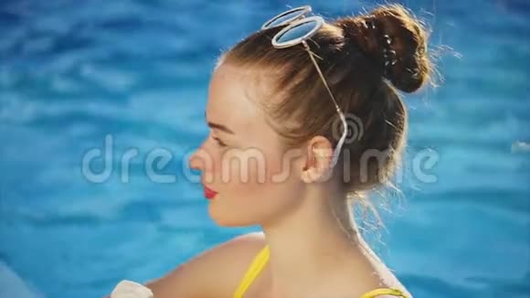迷人的女人在游泳池里放松时吃冰淇淋视频的预览图