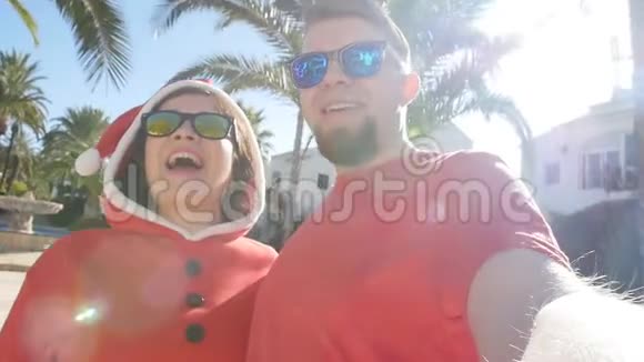 圣诞老人帽子上的快乐情侣在夏天的户外用手拍自拍照片视频的预览图