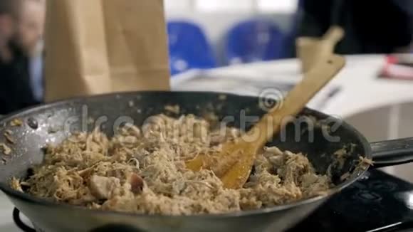 在餐厅的厨房里中年厨师在锅中用木勺把炸肉片和咸肉片拌匀视频的预览图