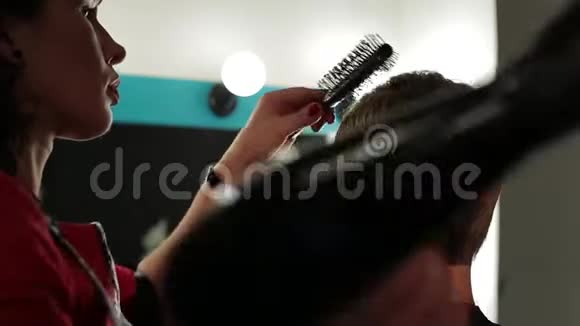 一个理发师人女理发师用吹风机吹干男性头部视频的预览图