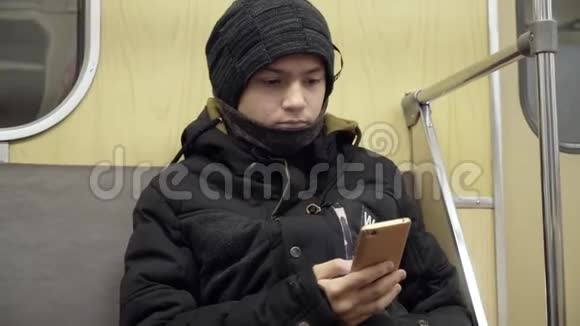 一个手里拿着智能手机的青少年正坐在地铁火车上用你的手机上网这就是视频的预览图