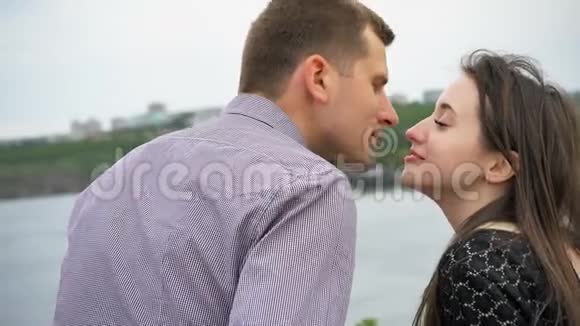日落时分在河边亲吻年轻夫妇男人和女人正在约会视频的预览图