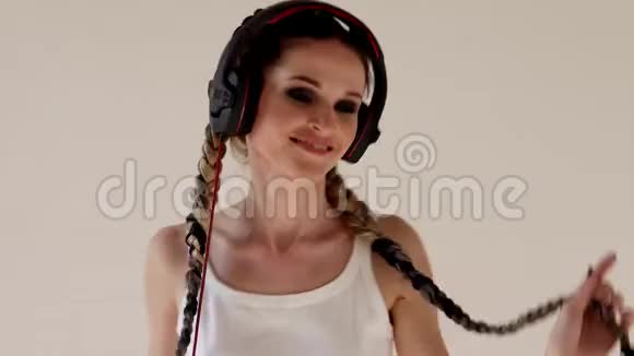 一个梳着辫子的女人用耳机听音乐跳舞视频的预览图