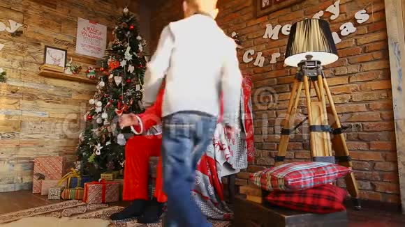 小男孩跑向圣诞老人把欲望放在圣诞老人的耳朵上视频的预览图