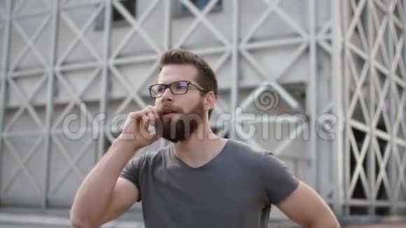 年轻的商人站在现代办公室附近和别人说话时髦的男人用智能手机打电话视频的预览图