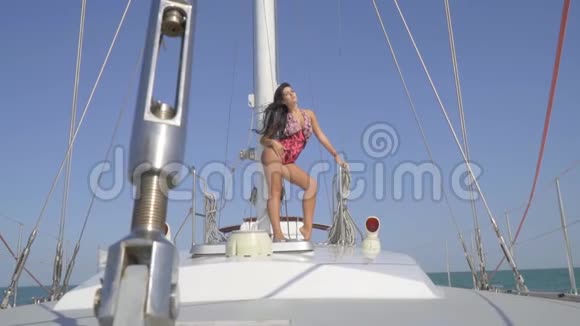 一位身穿泳装深褐色皮肤的美女站在一艘雪白的游艇中间迎着蓝天眺望视频的预览图