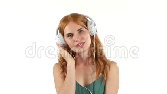 女孩通过耳机听她最喜欢的音乐白色背景视频的预览图