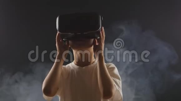 在一个烟雾弥漫的黑暗房间里男孩获得使用VR耳机的经验视频的预览图