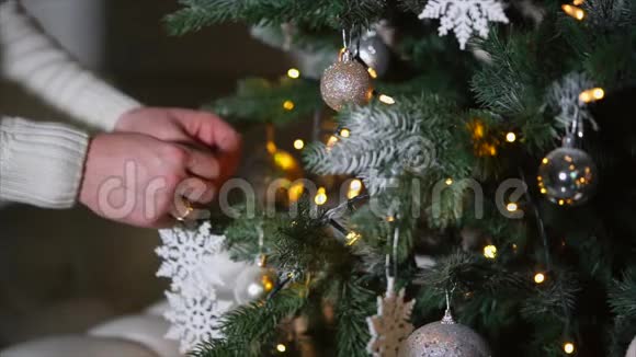 曼斯的双手正在黑暗的房间里把假的白色雪花放在圣诞树上视频的预览图