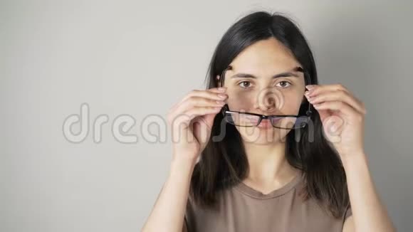 戴眼镜的女孩被隔离在灰色的墙壁背景上视频的预览图