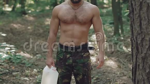 强壮的人从罐子里喝水然后自己倒在森林里视频的预览图