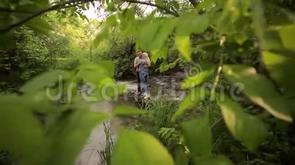 一对夫妇站在浅水河的岩石上视频的预览图