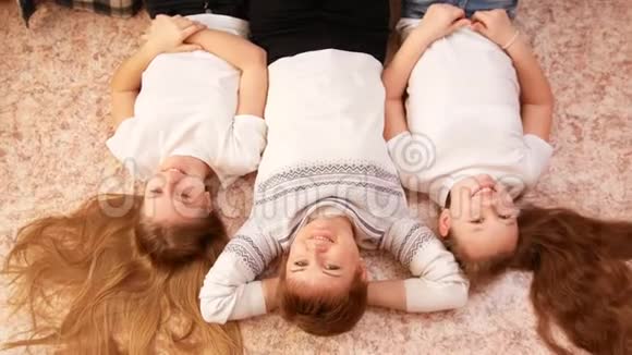 年轻的妈妈和她的两个十几岁的女儿躺在家里的地板上视频的预览图