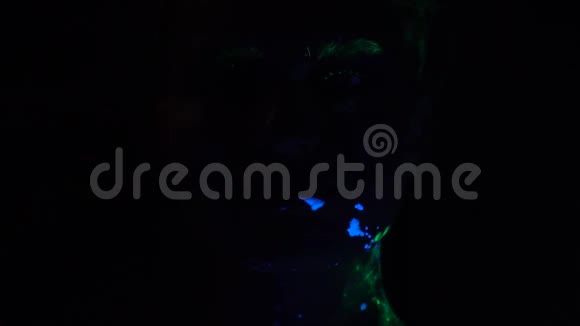 一个穿着荧光漆的女孩在黑暗中微笑看着相机视频的预览图