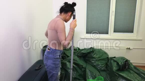 脏房间里有拖把和绿色塑料袋的女人视频的预览图