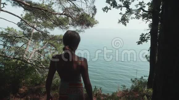 年轻快乐的白种人金发女郎举起双手在蓝色海洋背景的高岸上慢动作视频的预览图