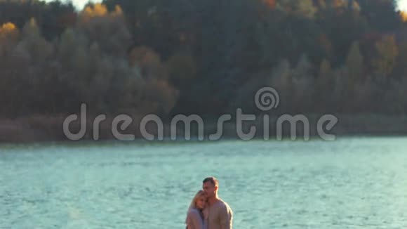 年轻夫妇穿着舒适优雅的毛衣站在河岸上拥抱着彼此的爱爱情故事永远视频的预览图