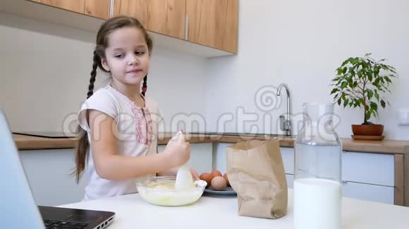 小女孩学会在厨房做饭用手提电脑做面包店视频的预览图