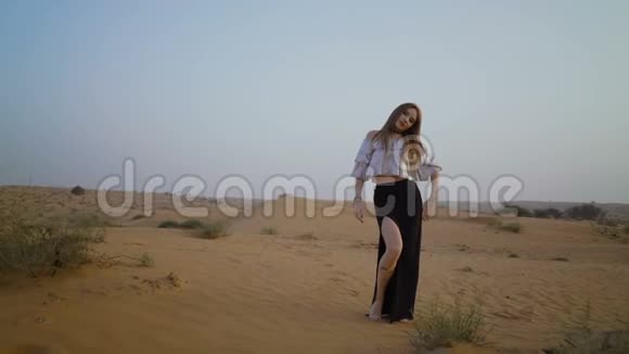 神秘的漂亮女孩走在沙漠里美丽的女人在日落时跳舞慢动作视频的预览图