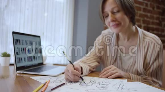 近距离拍摄创意时尚设计师的休闲服装查看笔记本电脑和绘制草图两个女人视频的预览图