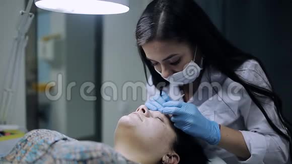 美容师在美容院给一个脸上长了粉刺的女孩修眉视频的预览图