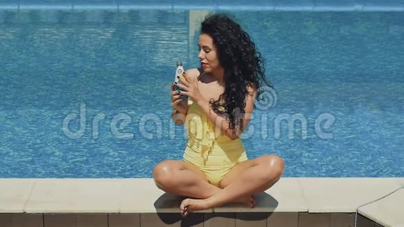 迷人的黑发女人在泳池边喝一杯蓝色鸡尾酒里面有罗勒籽视频的预览图