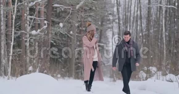 年轻的已婚夫妇相爱在冬天的森林里散步一男一女互相看着笑着进来视频的预览图