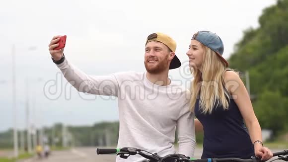 年轻夫妇骑自行车用智能手机拍照视频的预览图