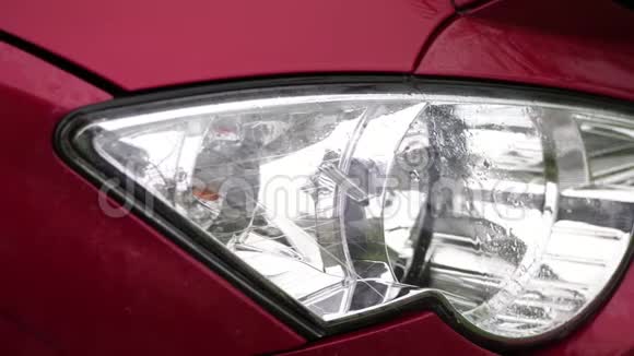 关门汽车前照灯淋浴时水滴溅落在红色汽车罩湿的表面玻璃前照灯视频的预览图