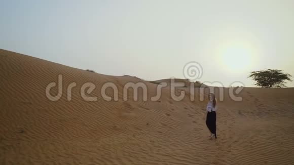 漂亮的女孩在沙漠里奔跑美丽的女人在日落时奔跑慢动作视频的预览图