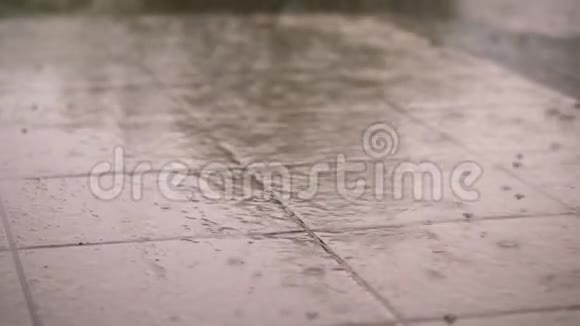 特写有大雨一阵阵雨大的大雨滴在街道瓷砖上雨滴湿地板的质地视频的预览图