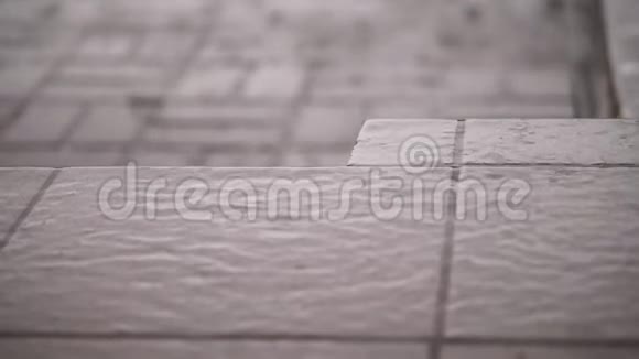特写有大雨一阵阵雨大的大雨滴在街道瓷砖上雨滴湿地板的质地视频的预览图