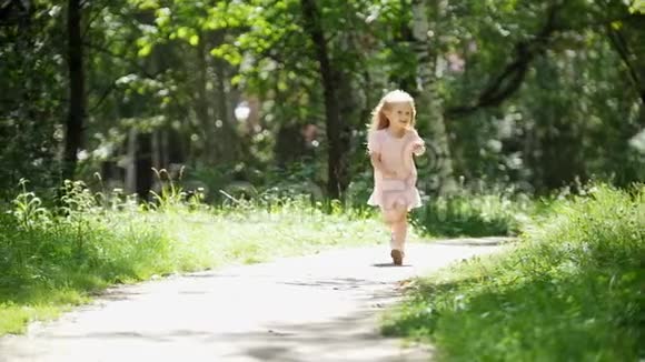 阳光明媚的一天一个金发小女孩在公园里奔跑慢镜头视频的预览图