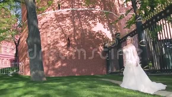 美丽的新娘穿着白色的夏装在砖墙的背景上视频的预览图