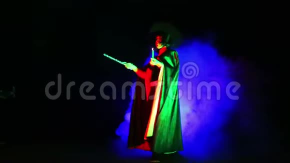 一个穿着黑色斗篷和帽子的年轻女巫手里拿着蜡烛烟雾缭绕视频的预览图