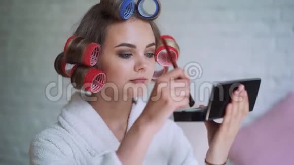 化妆年轻的女人涂口红戴着卷发器准备出门视频的预览图