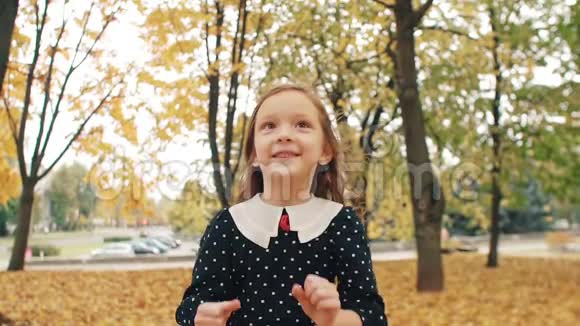肖像可爱的卷发小女孩穿着圆点花纹的裙子笑跳在秋天的公园里玩得很开心视频的预览图