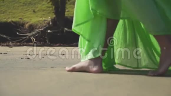 一个穿着绿色衣服在沙滩上行走的女孩的腿视频的预览图