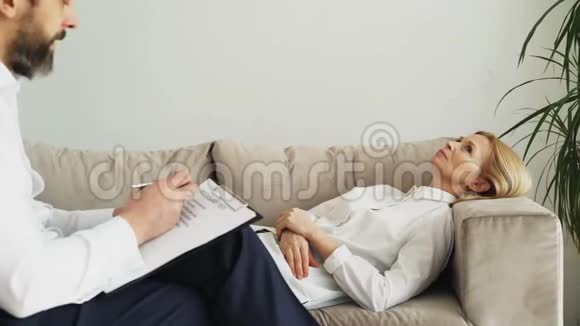 躺在沙发上的成年女性在谈论她与专业男性心理治疗师或心理学家的问题视频的预览图