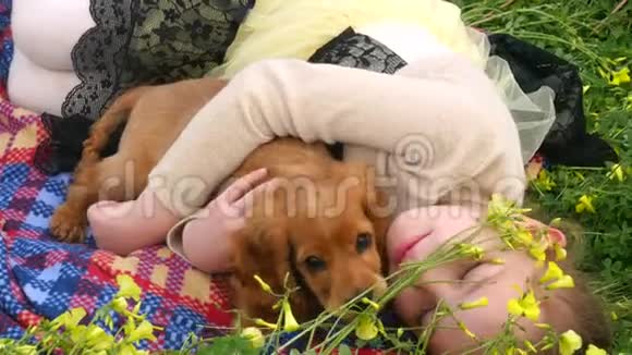 一个漂亮的女孩和一只小狗躺在草地上视频的预览图