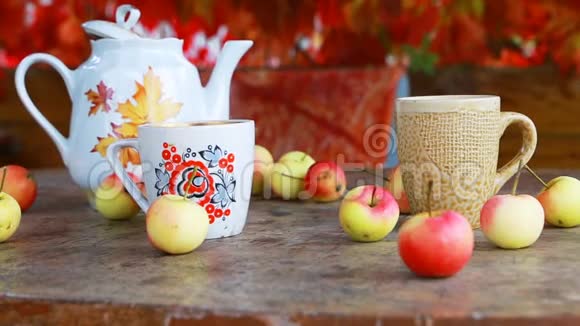 木桌上放着秋叶和苹果的茶杯视频的预览图