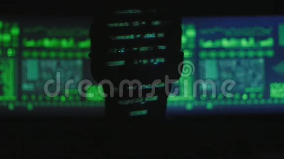 黑客程序员打开笔记本电脑的剪影而绿色代码字符在网络中反映他的脸视频的预览图